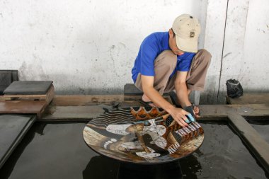 Bilinmeyen sanatçı bir tabak üzerinde bitmiş Cila Boya parlatır.