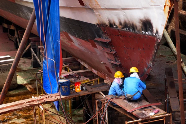 Shipyard workers repair a ship