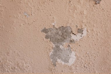 Binanın dış tarafında boya çatlakları olan eski bir beton duvar var..