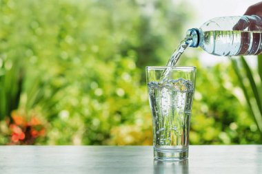 Bokhe doğa arka planına şişeden cama su dökmek 