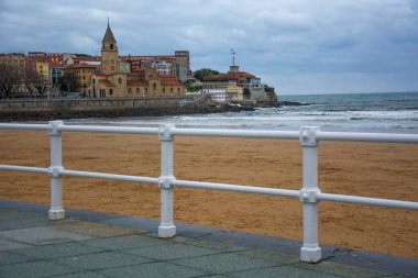 Bulutlu gökyüzü, beyaz korkuluklar ve soğuk renkler ile kilise cephesi.