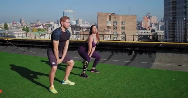 Doi sportivi, un bărbat și o femeie care fac un antrenament cu greutăți pe acoperișul clădirii. Conceptul dublu . — Videoclip de stoc