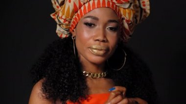 Geleneksel başlık güzel Afro-Amerikan genç kadın siyah arka planda tek başına kameraya bakıyor. Yüksek kaliteli 4k çözünürlük görüntüleri