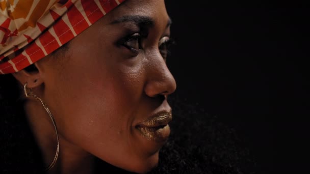 Siyah arka planda izole edilmiş kameraya bakan geleneksel Afro-Amerikan kadın başlığını kapatın. Yüksek kaliteli 4k çözünürlük görüntüleri — Stok video