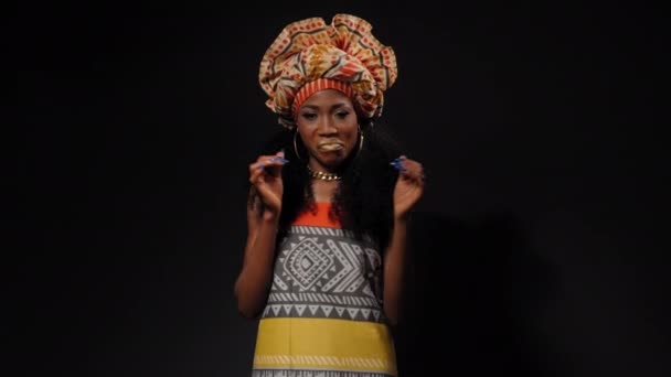 ハーフボディの撮影は、伝統的な美しいアフリカ系アメリカ人の若い女性のダンスや笑顔カメラを横に黒の背景に孤立見て美しい服。高品質4k解像度映像 — ストック動画