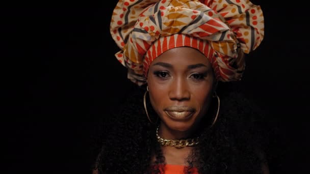 Tradycyjne nakrycie głowy piękna Afro amerykańska młoda kobieta patrząc w kamerę bokiem izolowane na czarnym tle. Wysokiej jakości materiał 4k rozdzielczości — Wideo stockowe