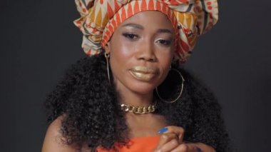 Geleneksel başlık güzel Afro-Amerikan genç kadın siyah arka planda tek başına kameraya bakıyor. Yüksek kaliteli 4k çözünürlük görüntüleri