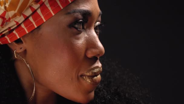 Närbild ansikte traditionella huvudbonad vacker afro amerikansk ung kvinna tittar på kameran isolerad på svart bakgrund. Högkvalitativ 4k-upplösning — Stockvideo