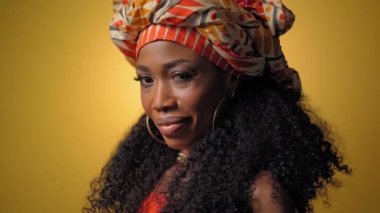 Güzel Afro-Amerikan genç kadın ulusal bir başlık takıyor sarı arka planda yanlamasına kameraya bakıyor. Yüksek kaliteli 4k çözünürlük görüntüleri