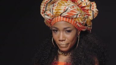 Gözlerinizi kameradan ayırmayın güzel Afro-Amerikalı kadın ulusal başlık takmış siyah arka planda izole edilmiş kameraya bakıyor. Yüksek kaliteli 4k çözünürlük görüntüleri