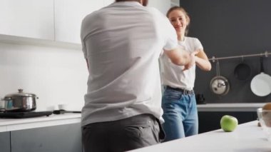 Tadilattan sonra bir evde mutlu bir çift. Yeni evde dans etmek, beyaz renkli modern mutfakta yemek pişiren sevgi dolu bir çifte dönüştü. Yeni bir aile için yeni bir ev. Yüksek çözünürlüklü