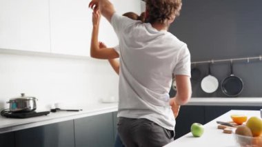 Tadilattan sonra bir evde mutlu bir çift. Yeni evde dans etmek, beyaz renkli modern mutfakta yemek pişiren sevgi dolu bir çifte dönüştü. Yeni bir aile için yeni bir ev. Yüksek çözünürlüklü