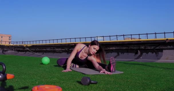 Atleta giovane donna che fa strette anche strette con allenamento di yoga gaiam spingendo il suo corpo giù sul tetto dell'edificio. Concetto di doppio. 10-18-17 Kiev, Ucraina. 4k UHD — Video Stock