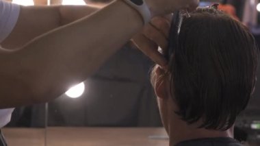 Yakın plan kadınların elleri saç kesimi için saç tarağını paylaşır. Kuafördeki müşteri oturup aynaya bakar. Yüksek kalite 4k görüntü.