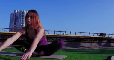 Genç atlet kadın, dizlerini binanın çatısına dayayarak sicim egzersizi yapıyor. 10-18-17 Kyiv, Ukrayna. 4k UHD