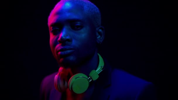 Chilling Concept. Night Club Life Portrait. Rich African American in Expansive Suit With Headphones at Party in Neon Light. Young Man Look in Camera. Close Up. High quality 4k footage — Stock Video