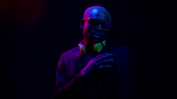 Nachtclubkonzept. Afroamerikaner tanzen auf Partys in Neons Nachts chillen Geschäftsleute auf der Tanzfläche. Ein junger Kerl bewegt sich in einem eleganten Anzug mit Brille und Kopfhörer. Hochwertige 4k Verfilmung — Stockvideo