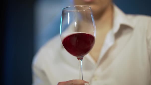 Аэрация вина. Концепция дегустации и виноделия. Женщина держит руку и слегка трясет стаканом красного вина. Размахивая красным вином в стекле. Высокое качество 4k Footage — стоковое видео