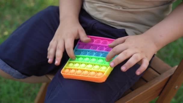 Niño sosteniendo arco iris pop it Fidget juguete en las manos. — Vídeo de stock