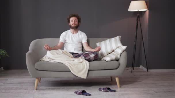 Meditáció lefekvés előtt. Fiatal srác lótuszpozícióban ül.. — Stock videók