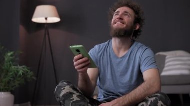 Akıllı telefonlu mutlu genç adam, telefondan haberleri okuyor. Yüksek kalite video iletisi. Yüksek kalite 4k görüntü