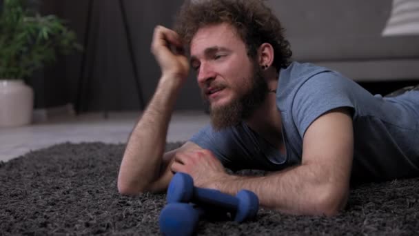 Hombre cansado después del deporte en el suelo. Deportista en alfombra. joven atleta con estilo de moda entrenado en casa. De la fatiga yace su cabeza sobre la alfombra. post de alta calidad — Vídeo de stock