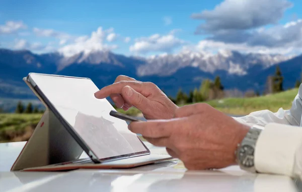 Tablet ve cep telefonu beyaz gömlekli bir adam tarafından tutuldu - doktor ya da iş adamı beyaz gömlekli bir adam tarafından elde tutulan verileri ve cep telefonunu analiz ederken - dağda yapılan akıllı iş