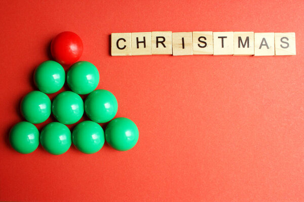 Зеленая елка из детской мозаики на красном фоне. Новогодние и рождественские украшения. - Почти. Объект слева. Концепция праздников. Флэтли. Вид сверху. Копирование пространства.