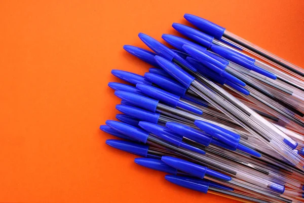 Ballpoint pens for writing on brown background. View from above. The case handles white, caps blue. Handles are located in the bottom right corner. Education. Schooling. For work. Flatlay. Copy spase.