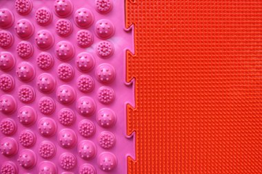 İki ortopedik paspas. Düz taban ve ayak masajını önlemek için parlak renkli paspaslar. Yukarıdan bak. Ortopedist. Önlem olarak. Pembe ve kırmızı hasırlar birleşti..