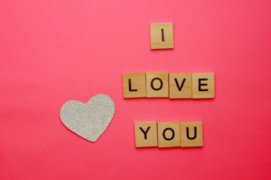 Pembe arka planda olmana bayılıyorum. Yazıtın yanında gümüş bir kalp var. Aşk konsepti. Sevgililer Günü. Romantizm. Geçmişi. Doku. Uzayı kopyala Flatlay. Yukarıdan görüntüle