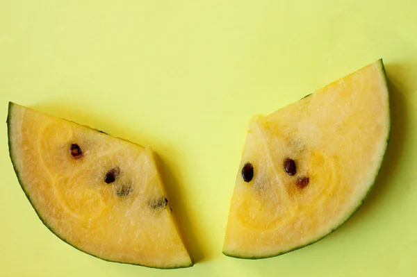 Two slices of yellow watermelon on a yellow background. Summer concert. A slice of watermelon. Delicious berry. Vitamins. Flat lay, top view, copy space