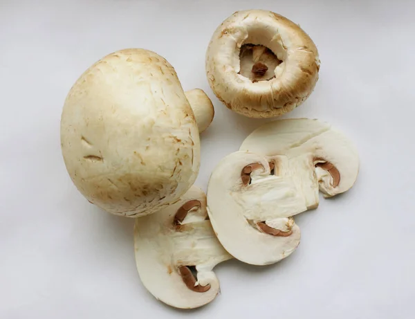 Champiñones. Vista desde arriba. Un hongo entero y al lado de las setas en rodajas sobre un fondo blanco. Deliciosas y saludables setas se cultivan en casa. Seta fresca cruda. Comida — Foto de Stock