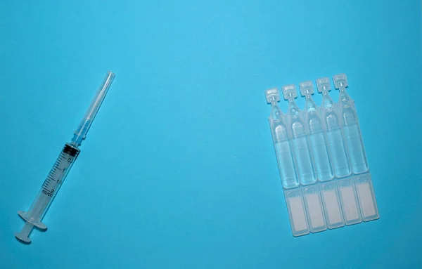 Ampullen Impfstoff und eine Spritze auf blauem Hintergrund. Impfen. Coronavirus. Das Konzept der Medizin und des Immunsystems. Impfungen gegen Virusinfektionen. Flach. Kopierraum — Stockfoto