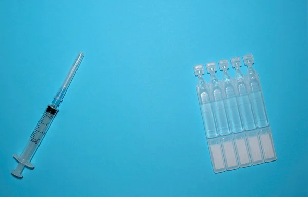 Aşı ampulleri ve mavi arka planda bir şırınga. Aşılama. Coronavirus. İlaç ve bağışıklık sistemi kavramı. Virüs enfeksiyonlarına karşı aşı. Dümdüz. Boşluğu kopyala