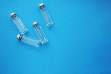 Mavi arka planda aşısı olan ampuller. Aşılama. Coronavirus. İlaç ve bağışıklık kavramı. Virüs enfeksiyonlarına karşı aşı. Dümdüz. Boşluğu kopyala.