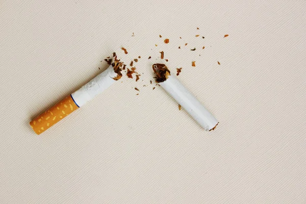 Eine kaputte Zigarette auf weißem Hintergrund. Tabakblätter sind rassistisch angehaucht. Blick von oben. Das Konzept von World No Tobacco, Tobacco and Lung Health. Gesundheitsschädlich. Schlechte Gewohnheit. — Stockfoto