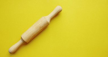 Sarı zemin üzerinde ahşaptan yapılmış hamura karşılık bir taş. Pişirme ve pişirme. Aşçılık. Yukarıdan bak. Uzayı kopyala Testin sonucu solda ezilmiş durumda. Pankart.