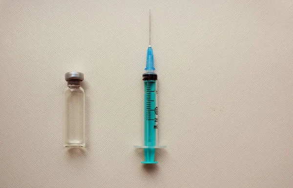 Eine Spritze mit Nadel, Medikamentenflaschen liegen auf einer medizinischen Maske auf hellem Hintergrund. Diktate und Immunität. Impfungen gegen Virusinfektionen. Medikament und Injektion. Injektion, Medikament. Kopierraum. — Stockfoto