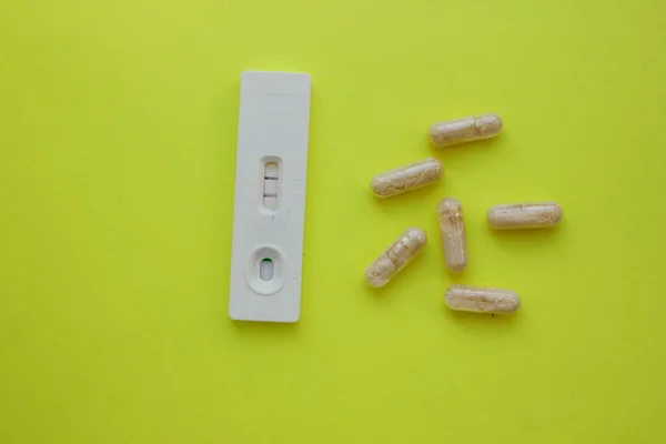 Positive pregnancy test and pills on a yellow background. Vitamins. Motherhood, children, pregnancy, the concept of birth control. Health problems and problems with conception. abortion. contraception — Stock Photo, Image
