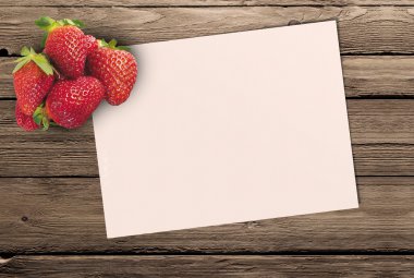 olgun çilek ve ahşap bir masa temiz bir sayfayla kağıda