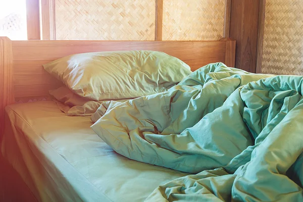 green pillow and blanket with wrinkle messy on bed in vintage wo