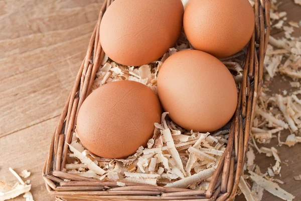 Ei auf Sägemehl mit altem Korb auf Holzgrund — Stockfoto