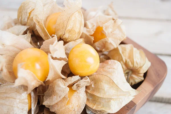 Uva spina del Capo (Physalis) in ciotola di legno sul tavolo di legno, guarire — Foto Stock