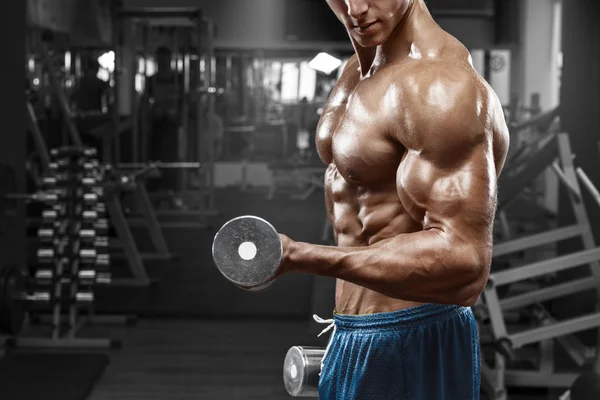 Spierman aan het sporten in de sportschool doet oefeningen met halters bij biceps, sterke mannelijke naakte bovenbuik — Stockfoto