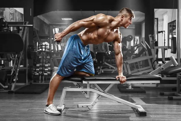 Kaslı adam egzersizleri triceps, güçlü erkek çıplak gövde abs, dumbbells ile yapıyor spor salonunda egzersiz