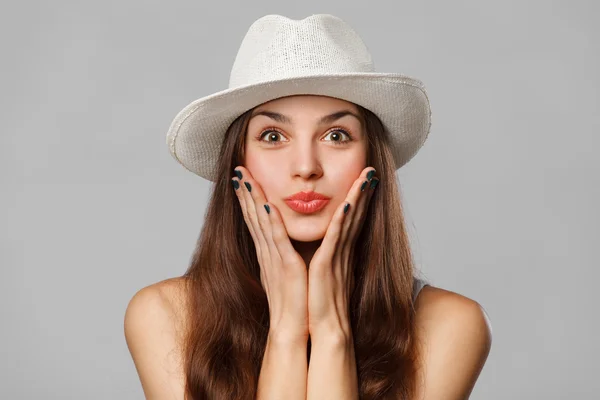 Surprised happy woman looking sideways in excitement. Excited girl in hat, isolated on gray background