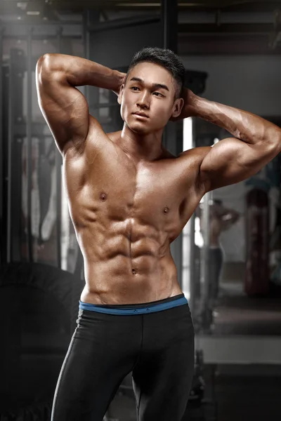 Сексуальный азиатский мускулистый мужчина позирует в спортзале в форме брюшной полости. Сильный обнаженный мужской пресс, тренируется — стоковое фото