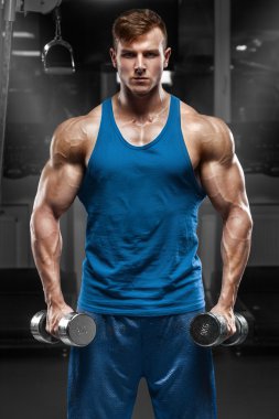 Kaslı adam dumbbells, güçlü erkek gövde ile egzersizleri yapıyor spor salonunda egzersiz