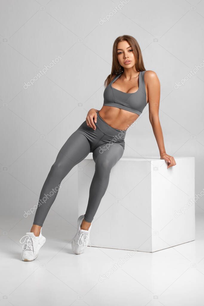 Beautiful fitness woman. Athletic girl on the gray background